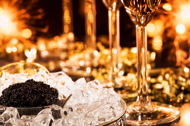 Black caviar on ice with champagne glasses on festive background